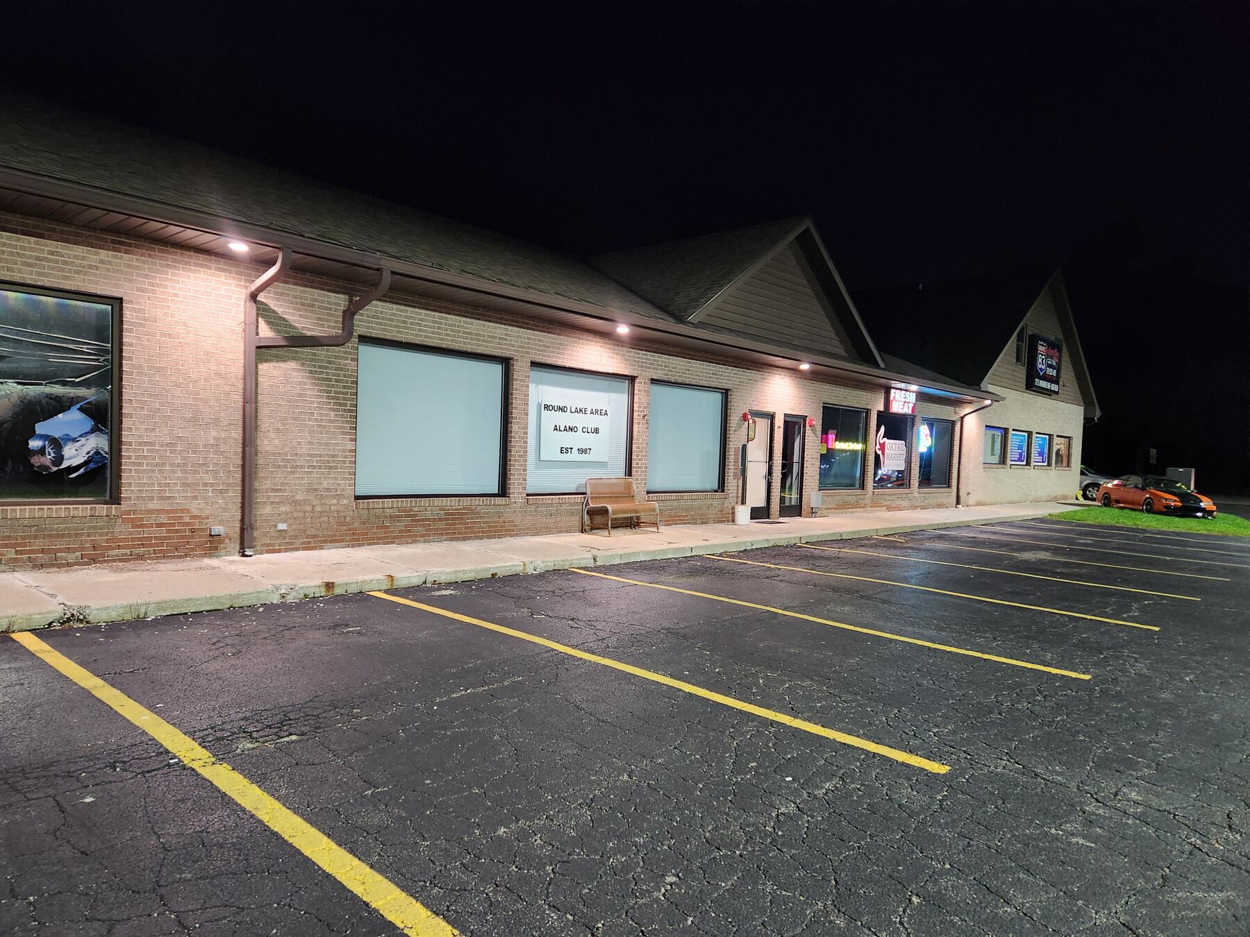 The club’s storefront and parking lot at night